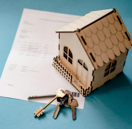 A bunch of keys and a model of a home placed at the table
